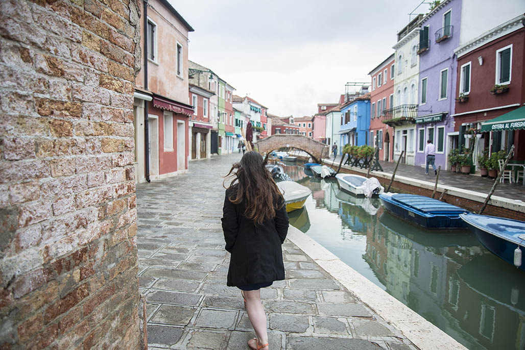 Me (woman) walking through burano canals for my italy winter packing list article